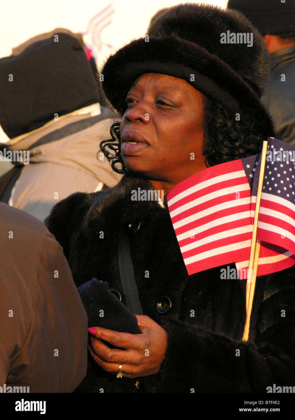 Donna afro-americana detiene bandierine americane come lei di ceppi per una vista tra la folla a Barack Obama inaugurazione. Foto Stock