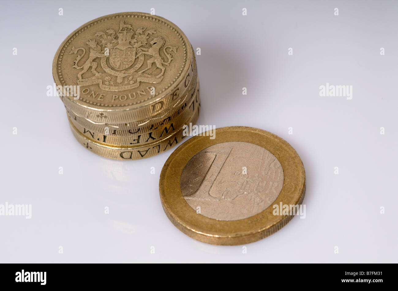 Foto di stock di un singolo Euro moneta accanto a una pila di lira sterlina monete Foto Stock