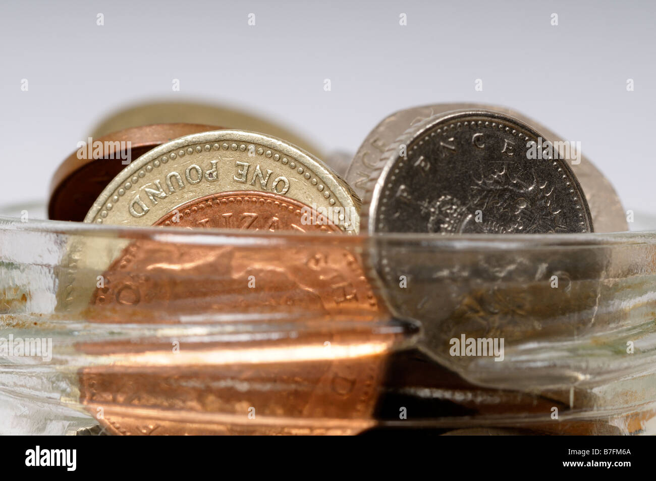 Foto di stock di una pila di sterling monete in un vasetto di marmellata Foto Stock