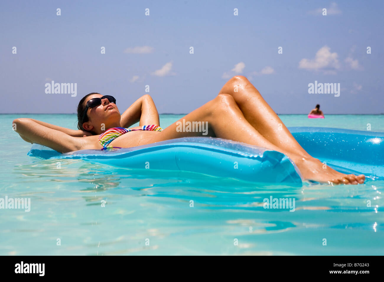 Un modello si rilassa su un lilo nell'oceano Foto Stock