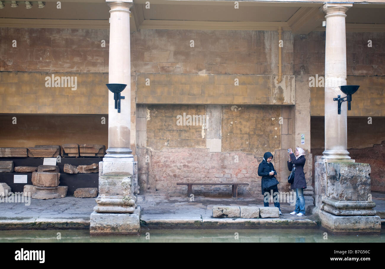 Due turisti giapponesi ad ascoltare la storia dei romani al bagno romano a Bath, Regno Unito Foto Stock