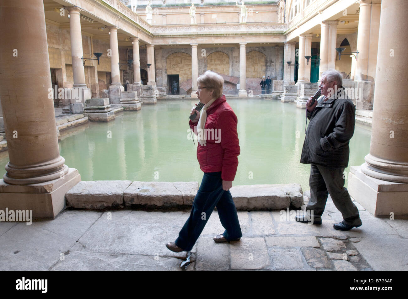 Due turisti di ascoltare la storia di romani al bagno romano a Bath, Regno Unito Foto Stock