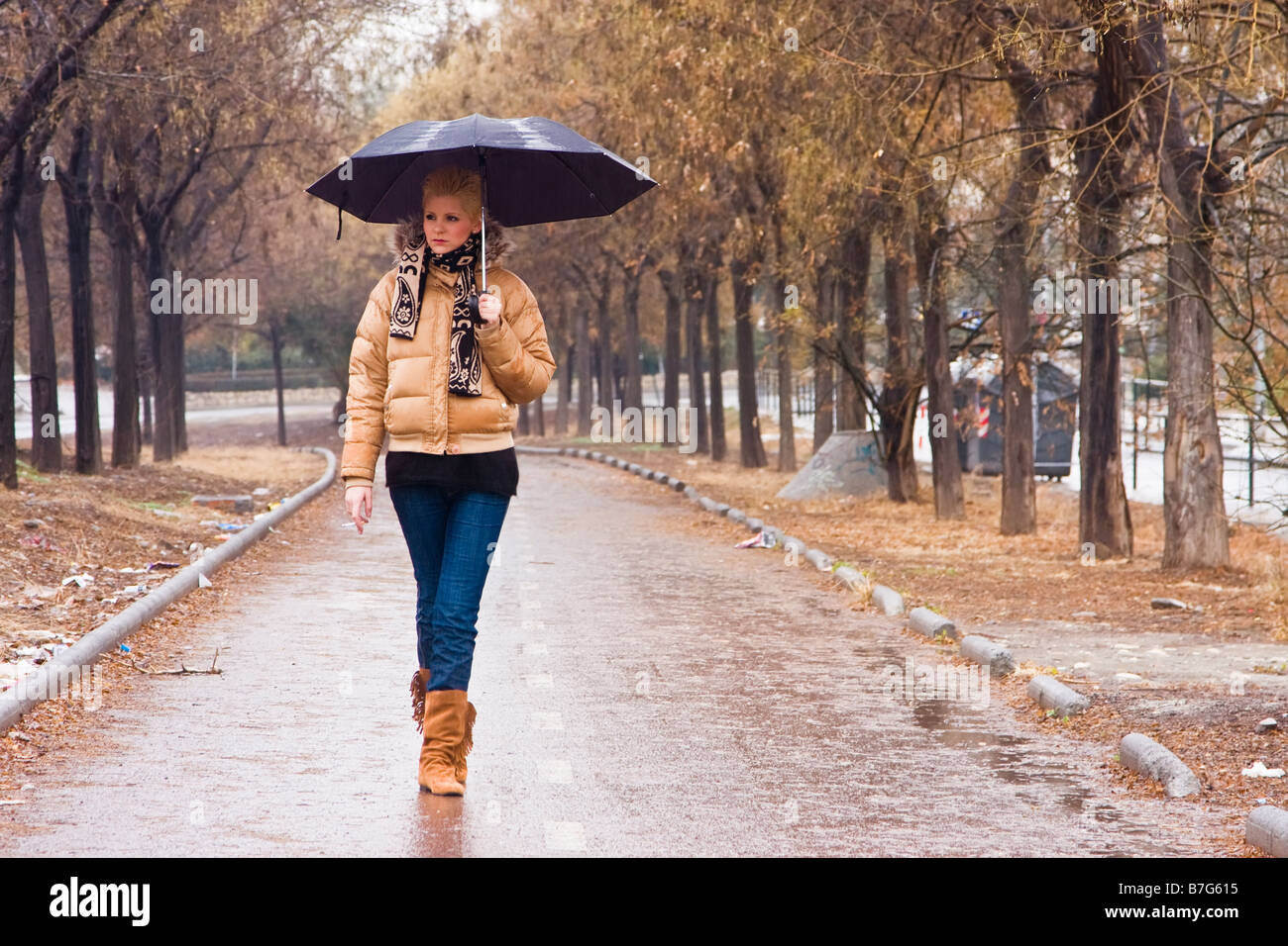 Bionda e giovane donna urbano camminano sotto la pioggia Foto Stock