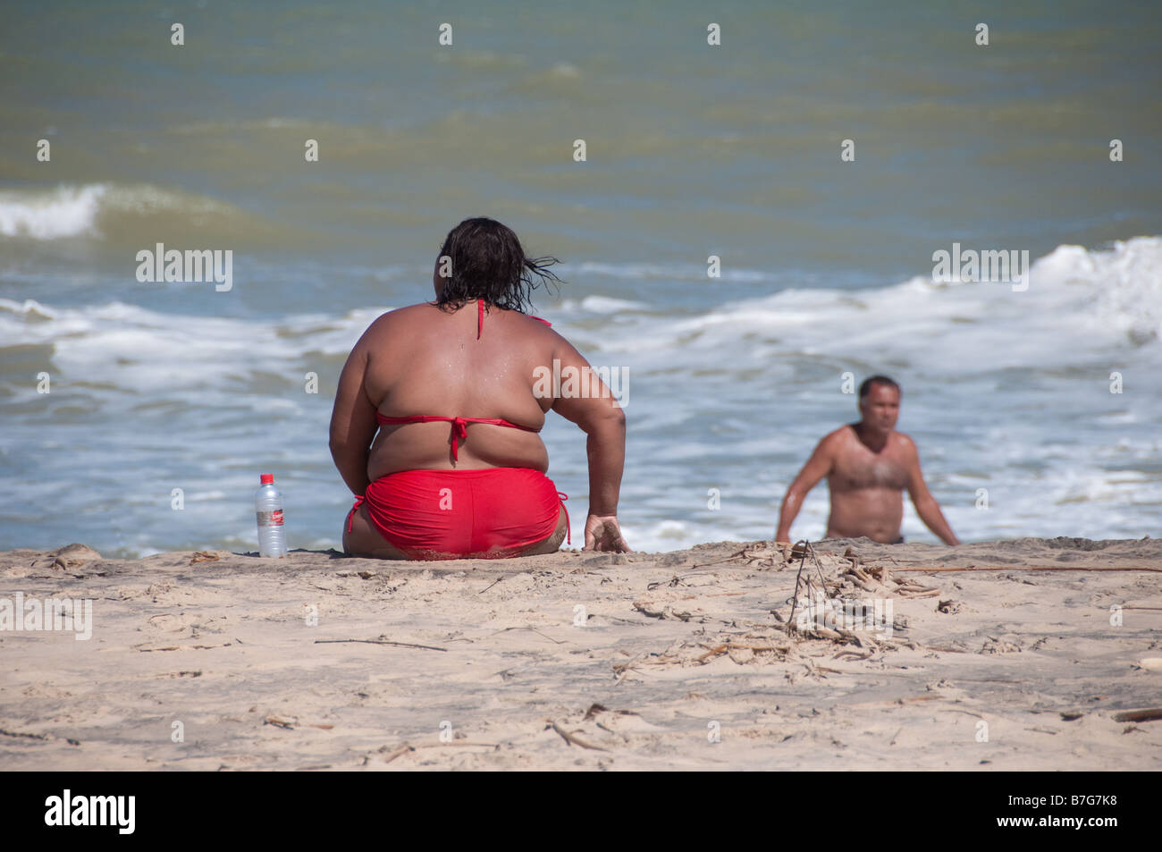 Una grande donna grassa si siede sulla spiaggia con un rosso swin suit Piacabucu è un nome indiano per l'ultima città sul fiume Foto Stock