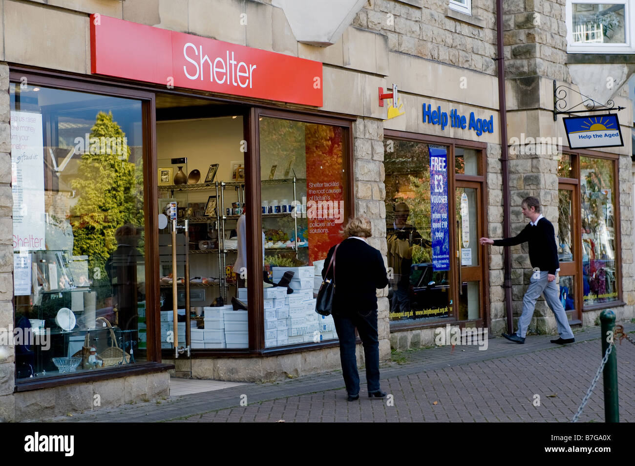 Gli amanti dello shopping passando e visitando i negozi caritatevoli in Ilkley, West Yorkshire Foto Stock