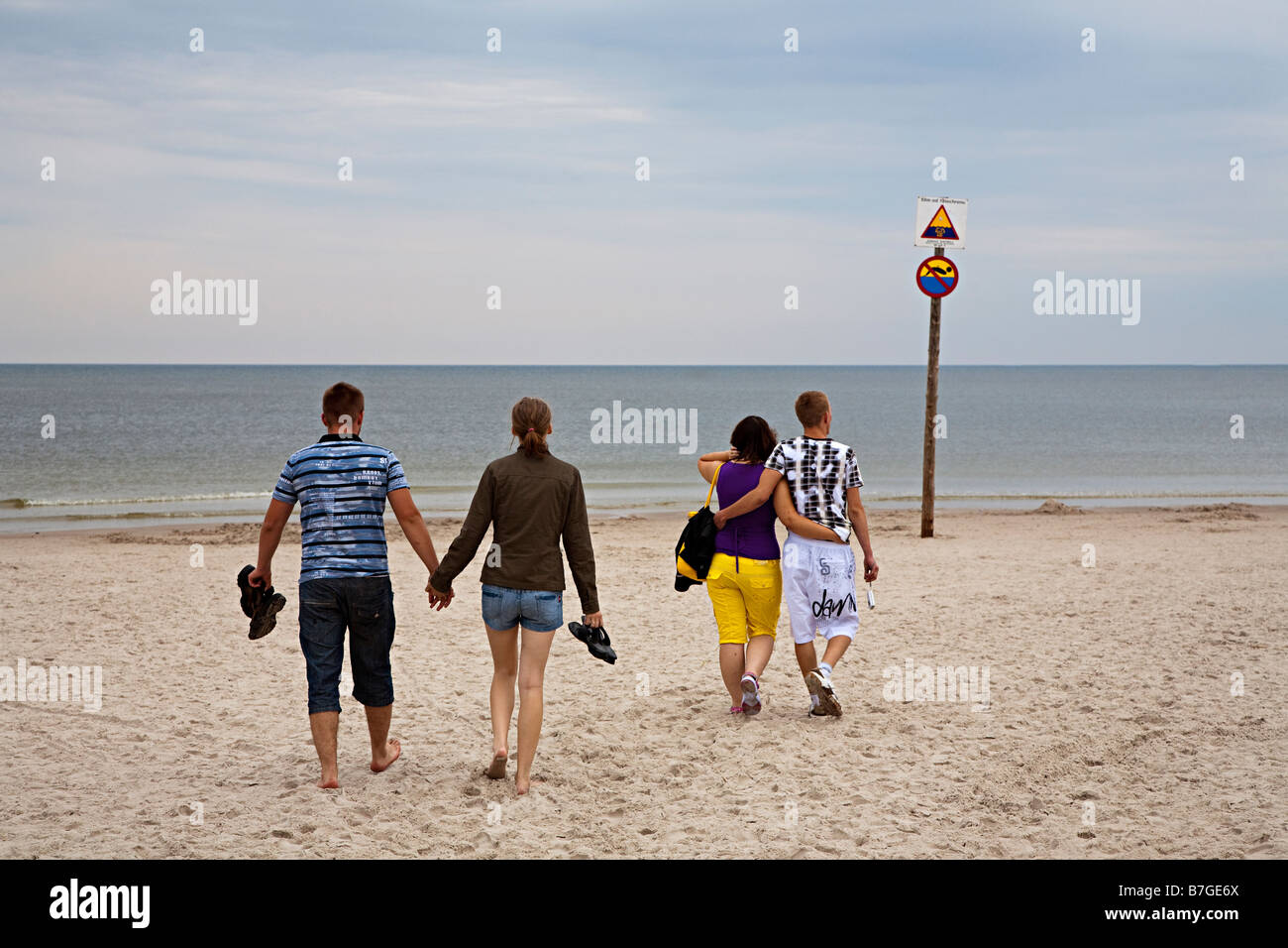 Due coppie giovani peoplle camminando mano nella mano sulla spiaggia al Mar Baltico località balneare di Leba Polonia Foto Stock