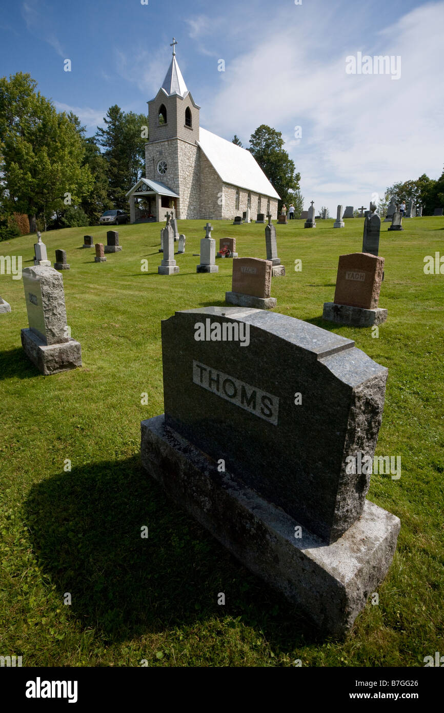 Chiesa e cimitero: una semplice chiesa del paese sorge su una collina circondata da pietre tombali Foto Stock