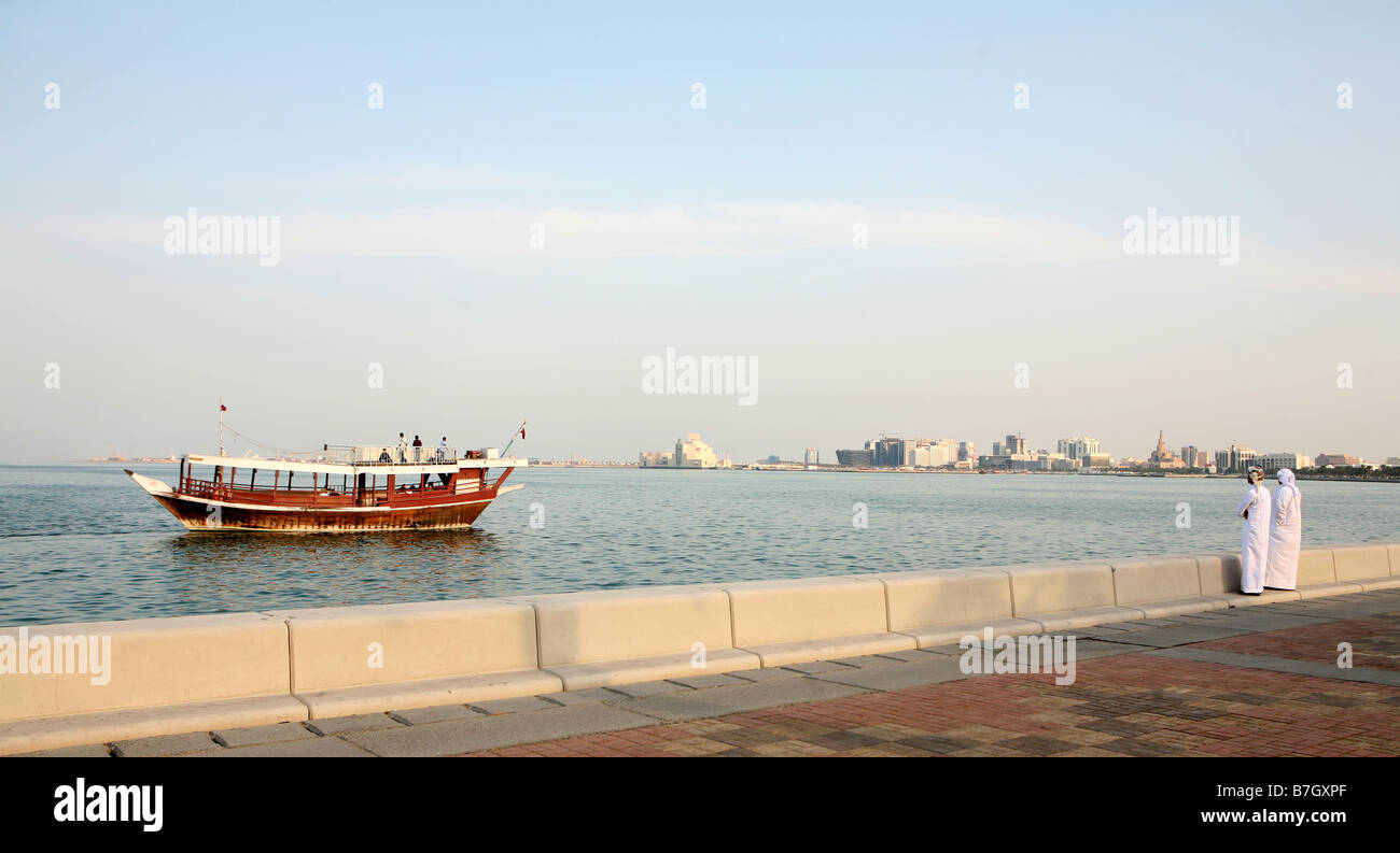 Due locali arabi si affacciano su Doha Bay mentre un dhow con turisti a bordo passa da gennaio 2009 Foto Stock