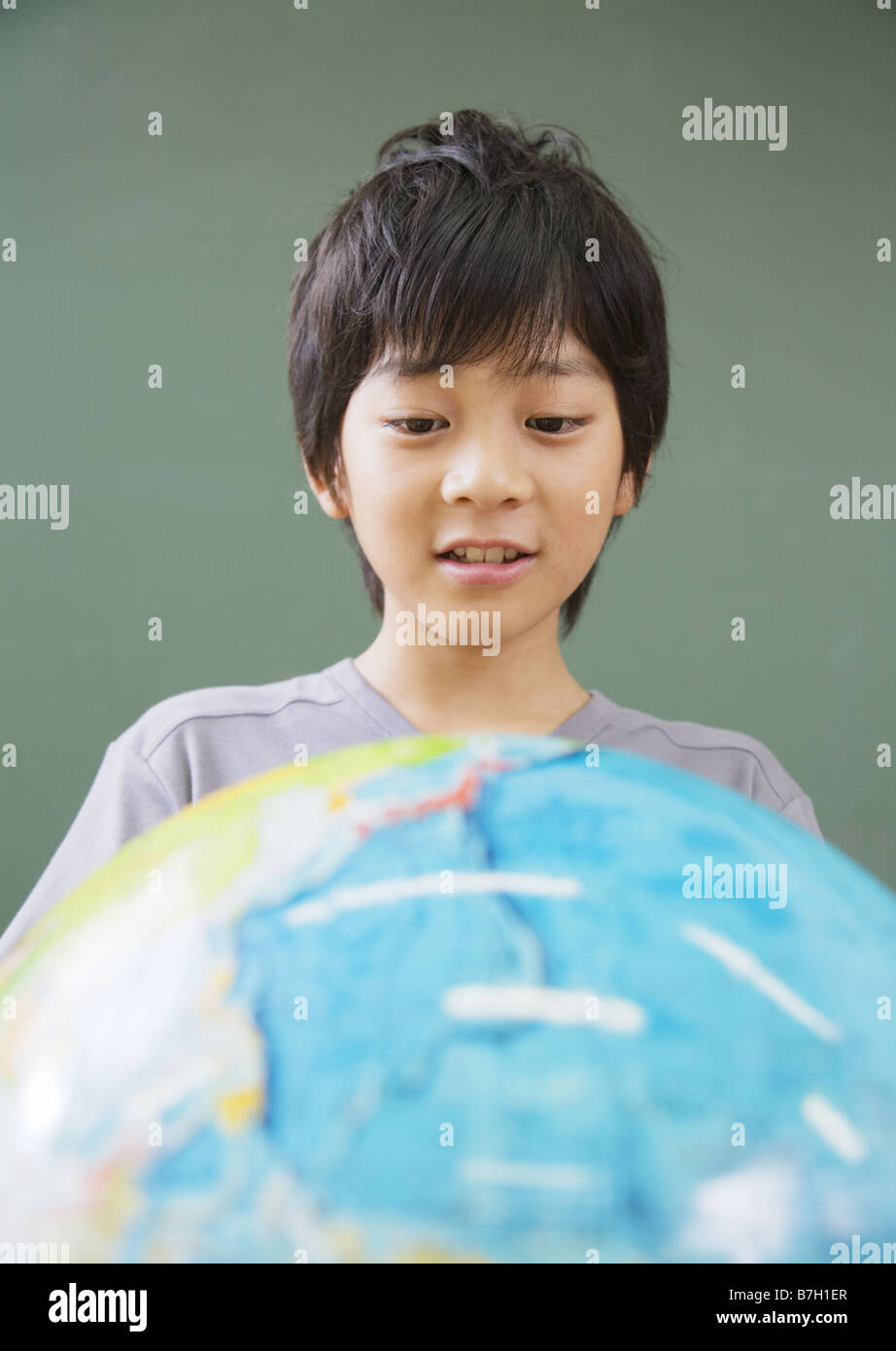 Scuola elementare boy guardando il globo terrestre Foto Stock