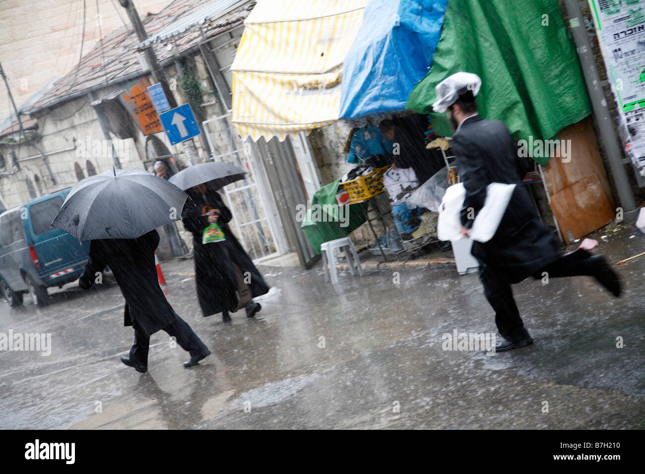 Gli Ebrei religiosi che attraversa le strade di Mea Shearim un quartiere religioso a Gerusalemme sotto la pioggia. Foto Stock