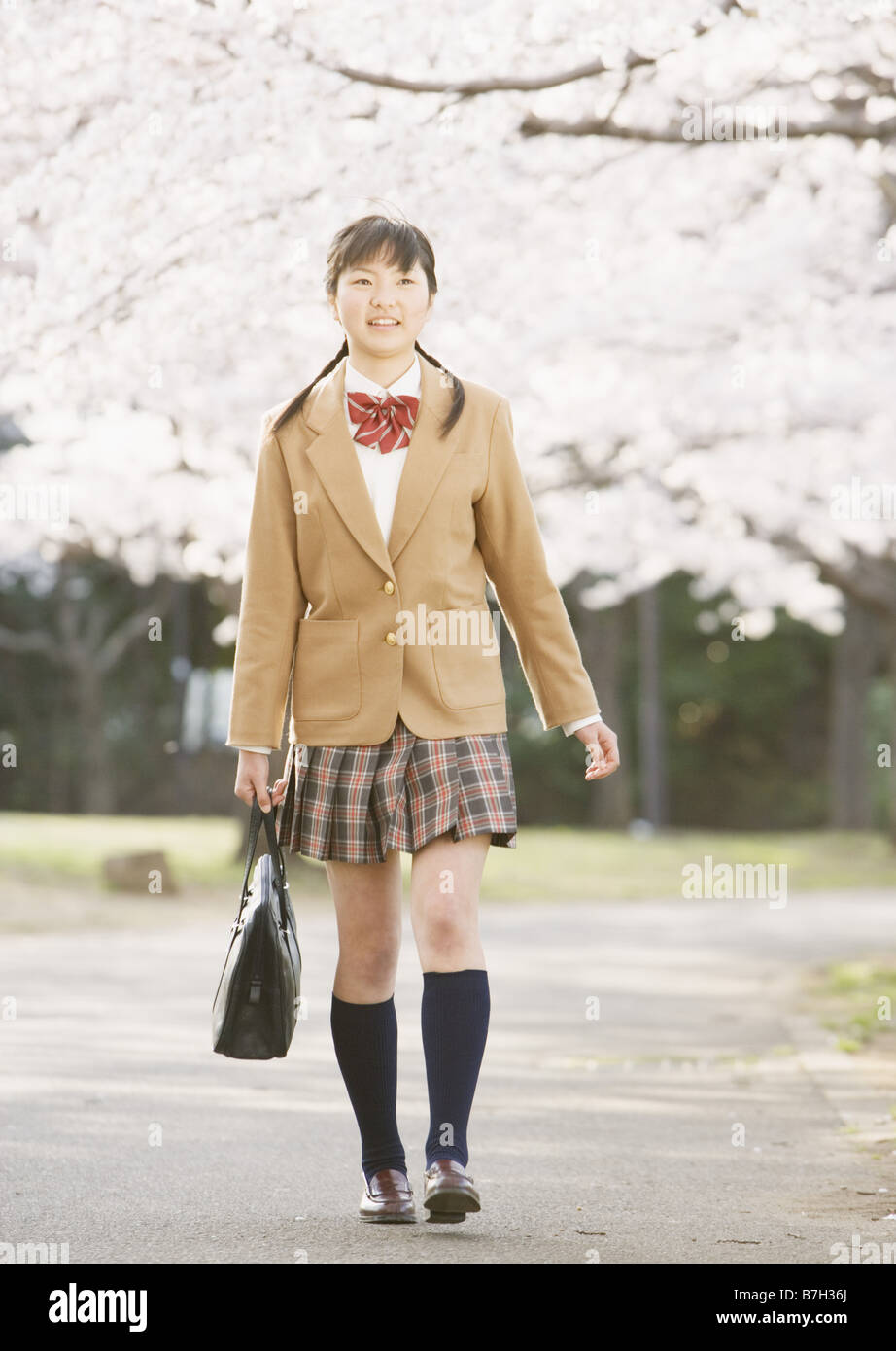 Teenagegirl camminare sotto la fioritura dei ciliegi alberi Foto Stock