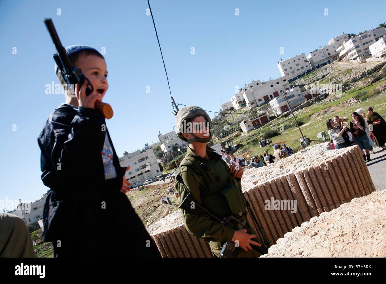 Coloni israeliani bambino con una pistola giocattolo celebrare la festa di Purim un ebreo festival religiosi israeliani occuparono la città vecchia di Hebron. Foto Stock