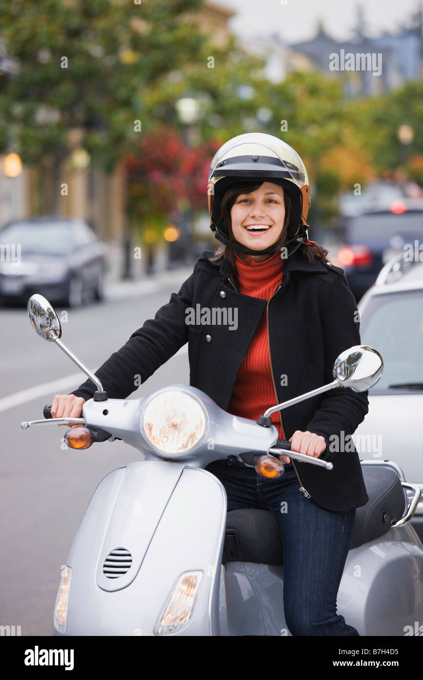 Razza mista donna nel casco scooter di guida Foto Stock