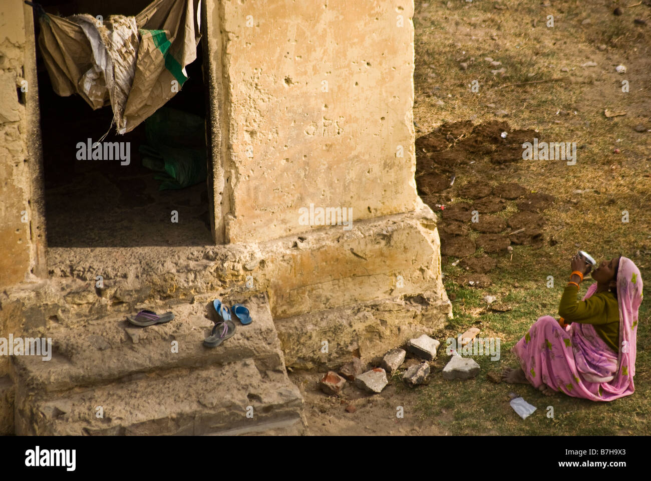 Una donna di bere quello che è probabilmente l'acqua sporca al di fuori del suo live-in shack, un minuscolo 4x4 capannone di utilità. Foto Stock