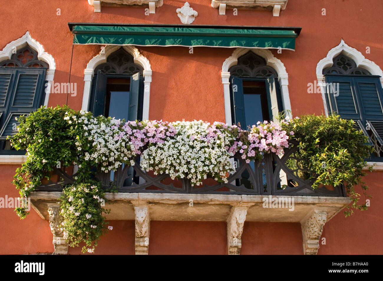 La colorata facciata di una casa e di un balcone traboccante di fiori in Venezia, Italia. Foto Stock