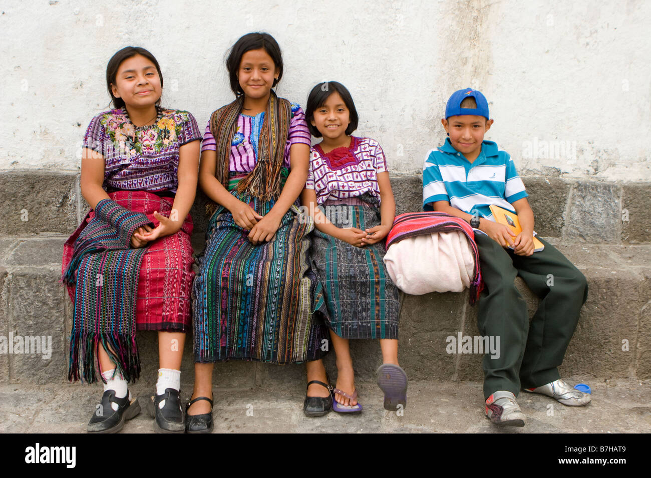 Bambini guatemaltechi in abito tradizionale rilassarsi al di fuori di una chiesa di Santiago Atitlan, Guatemala Foto Stock