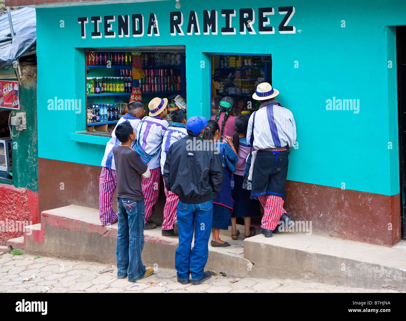 Un gruppo locale di guatemaltechi di guardare la televisione attraverso una tienda finestra sulla strada di Todos Santos Cuchumatan, Guatemala Foto Stock