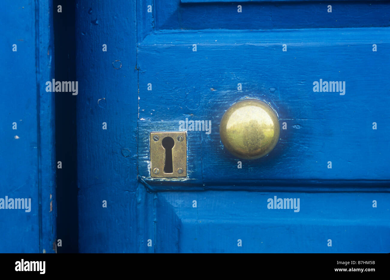Dettaglio di colore blu scuro con pannelli verniciati porta con ben utilizzato maniglia in ottone e piastra keyhole in piedi leggermente socchiuse Foto Stock