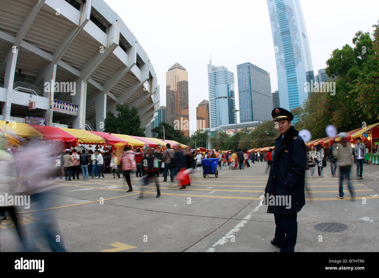 Uomo di polizia osservando attentamente come io fotografo Guangzhou Flower Expo con edifici di uffici e stadium di skyline Citic Plaza il Foto Stock