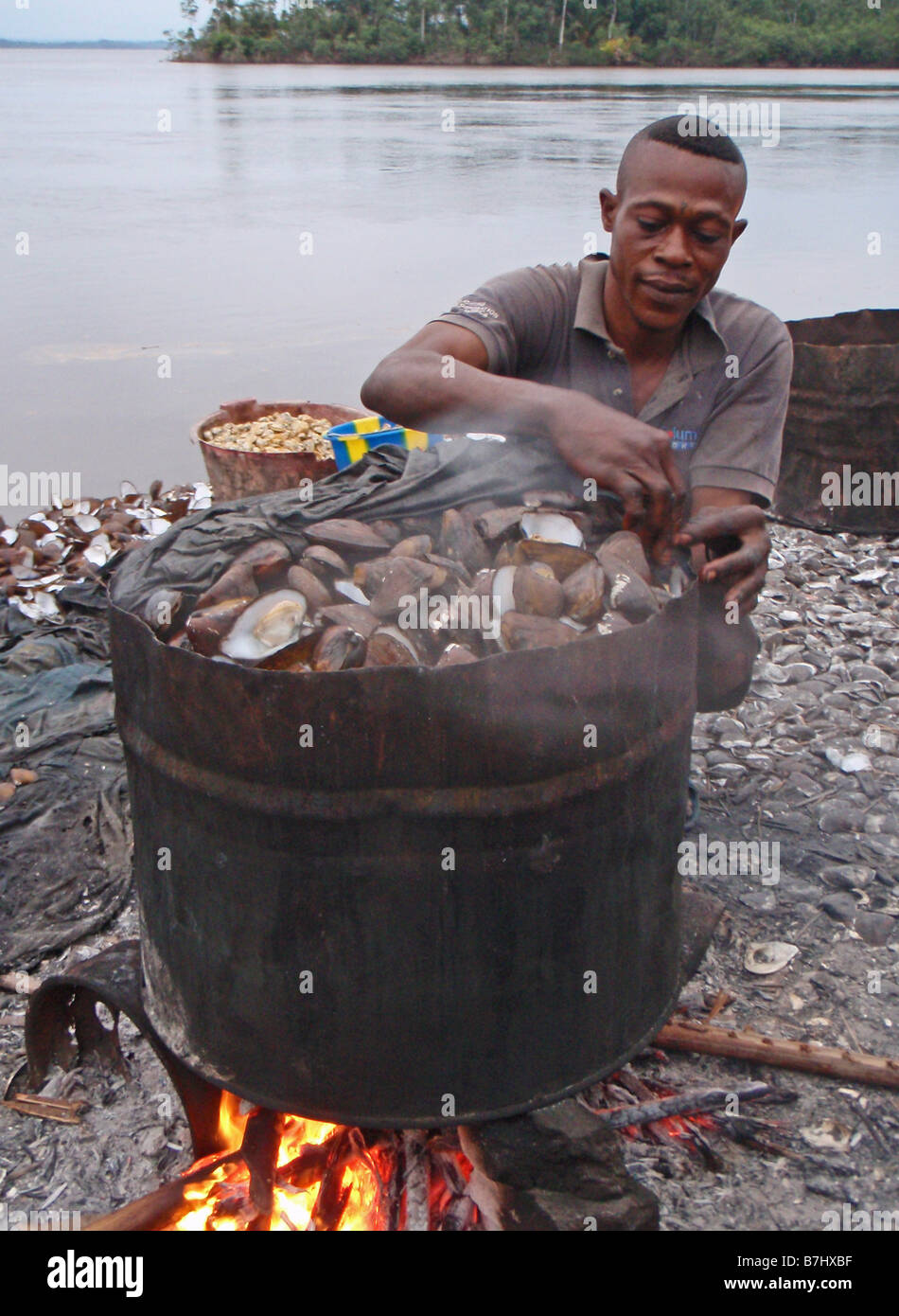 Fisherman ebollizione cozze vongole ostriche pesce a guscio in metallo grande tamburo di ferro sulle rive del fiume Congo Repubblica Democratica del Congo Foto Stock