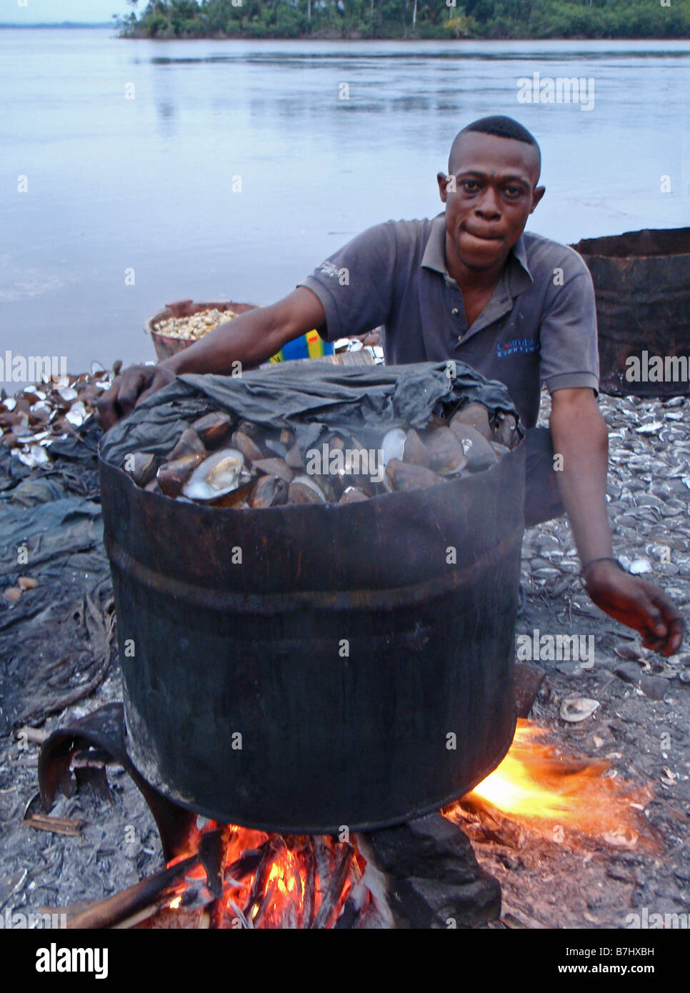 Fisherman ebollizione cozze vongole ostriche pesce a guscio in metallo grande tamburo di ferro sulle rive del fiume Congo Repubblica Democratica del Congo Foto Stock