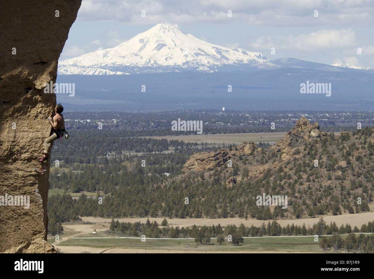 Man (25-30) arrampicata su roccia con la montagna in background, Smith Rock State Park, Oregon, Stati Uniti d'America Foto Stock