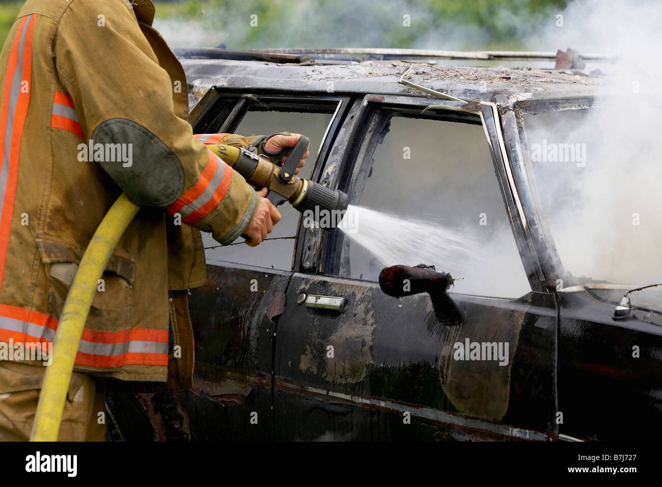 Fire Fighter mettendo fuori fuoco auto con tubo flessibile, Smithville, Ontario Foto Stock