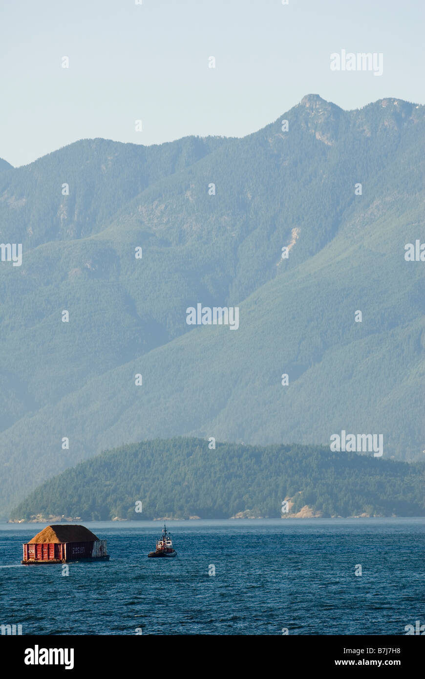 Rimorchiatore registri di trazione attraverso l'oceano con le montagne sullo sfondo, Howe Sound, BC Foto Stock