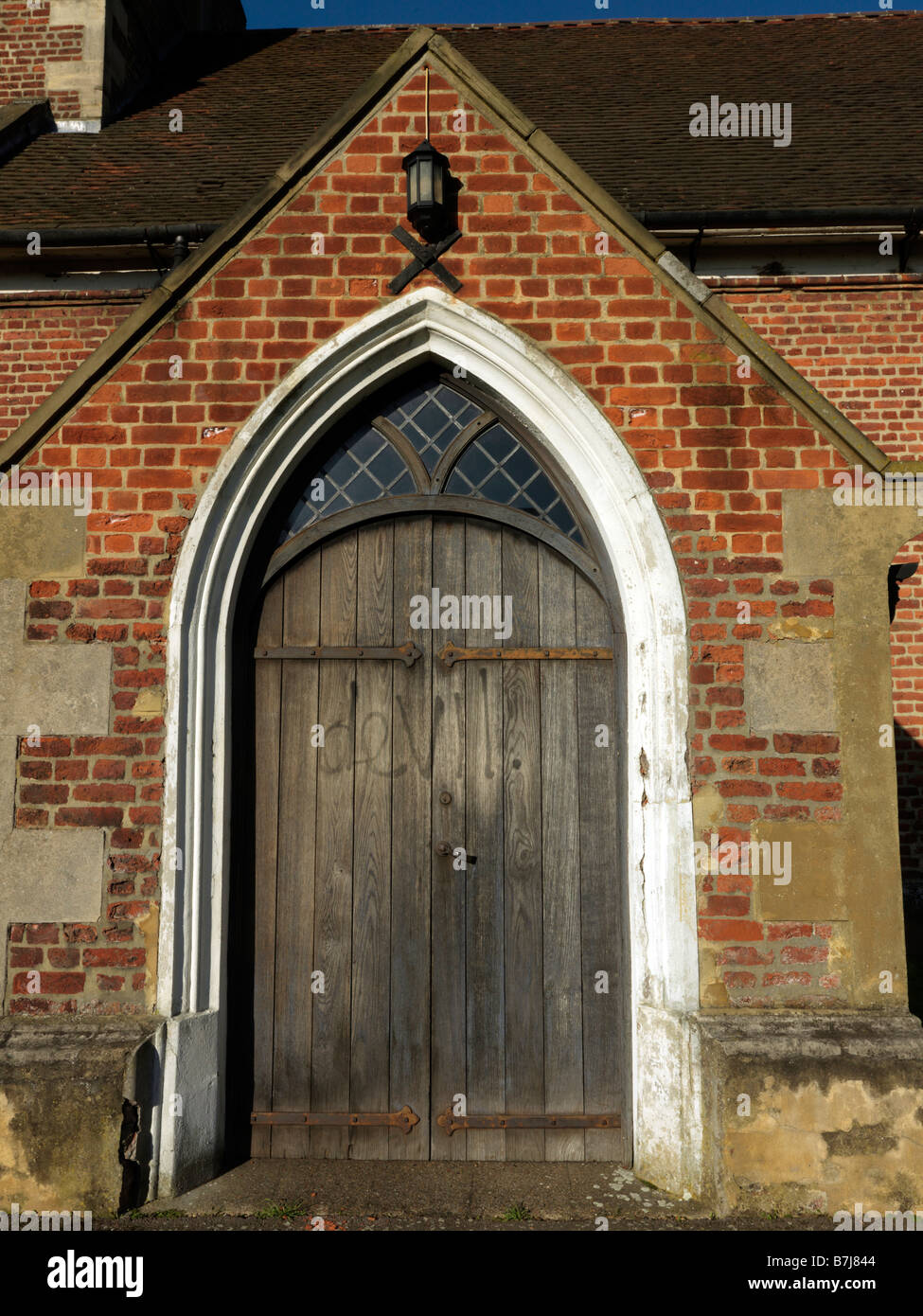 Chiesa di San Lorenzo Morden Surrey in Inghilterra Entrata Principale con graffiti Devil scritta sulla porta Foto Stock