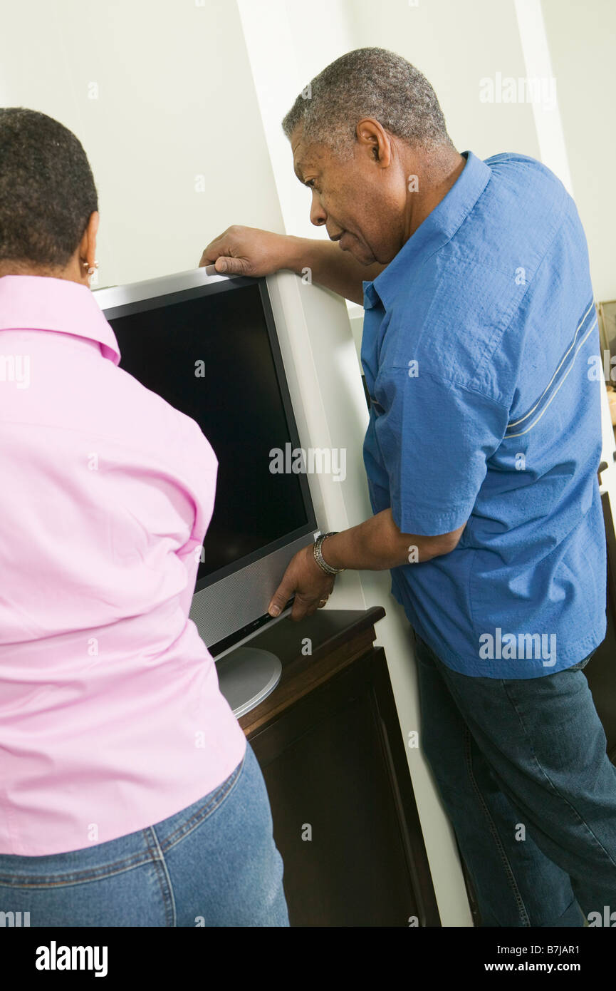 African American giovane installando una tv a schermo piatto, Vancouver, BC Foto Stock