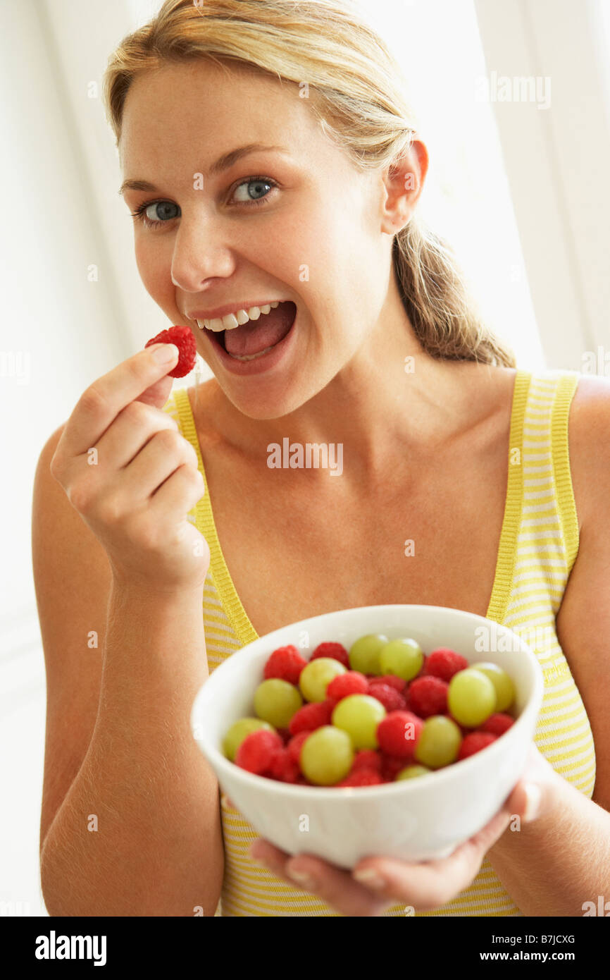 Giovane donna mangiare una tazza di frutta Foto Stock