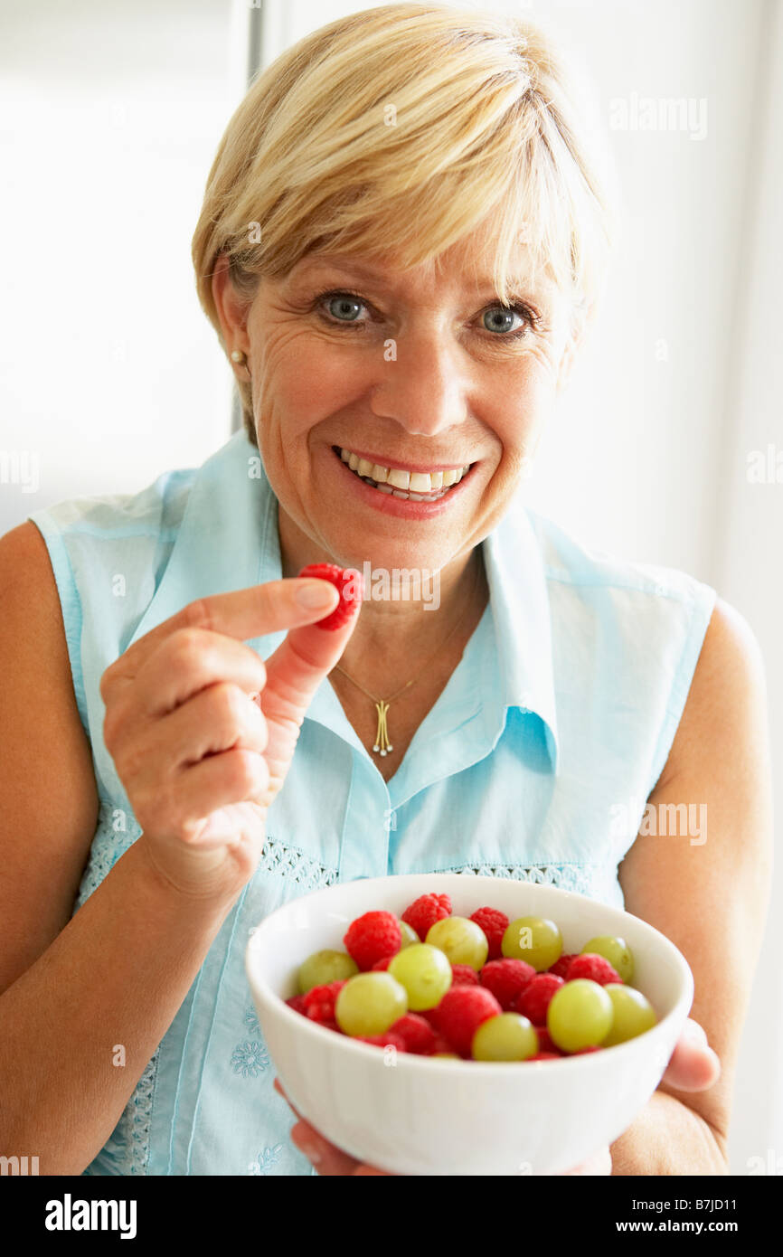 Donna di mezza età mangiare una tazza di frutta Foto Stock