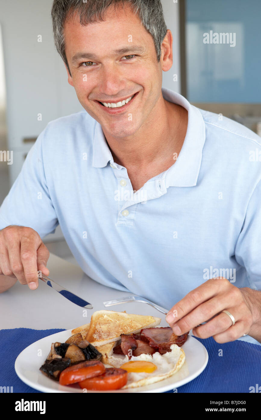 Uomo di mezza età mangiare malsano colazione fritta Foto Stock