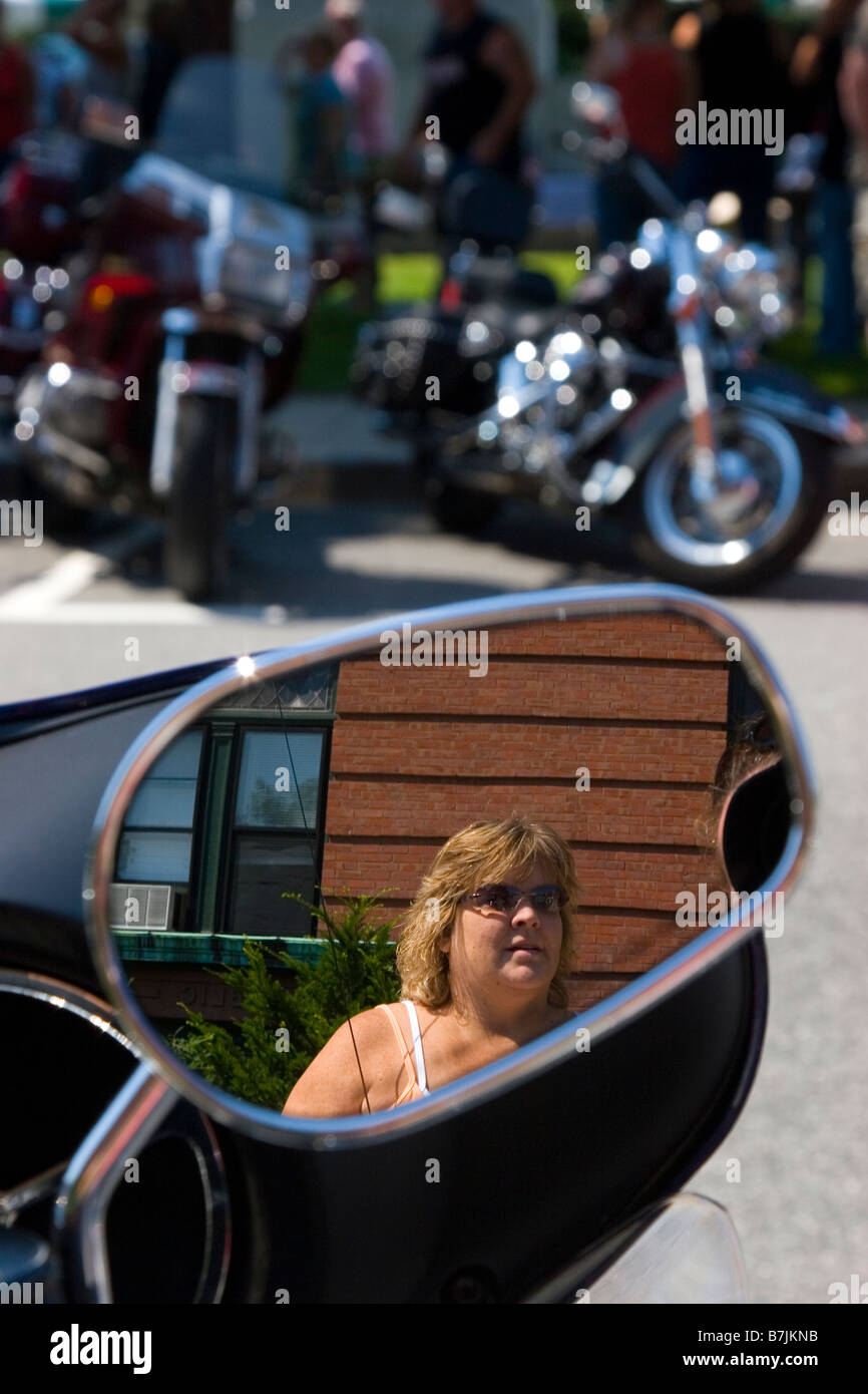 Donna di riflessione nel lato specchio della sua motocicletta Motocicletta specchio Foto Stock