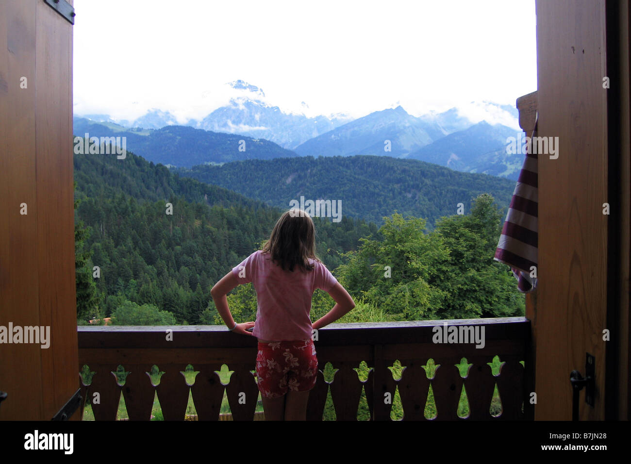 Una bambina guarda al di fuori della sua vacanza Alpine chalet, Svizzera Foto Stock