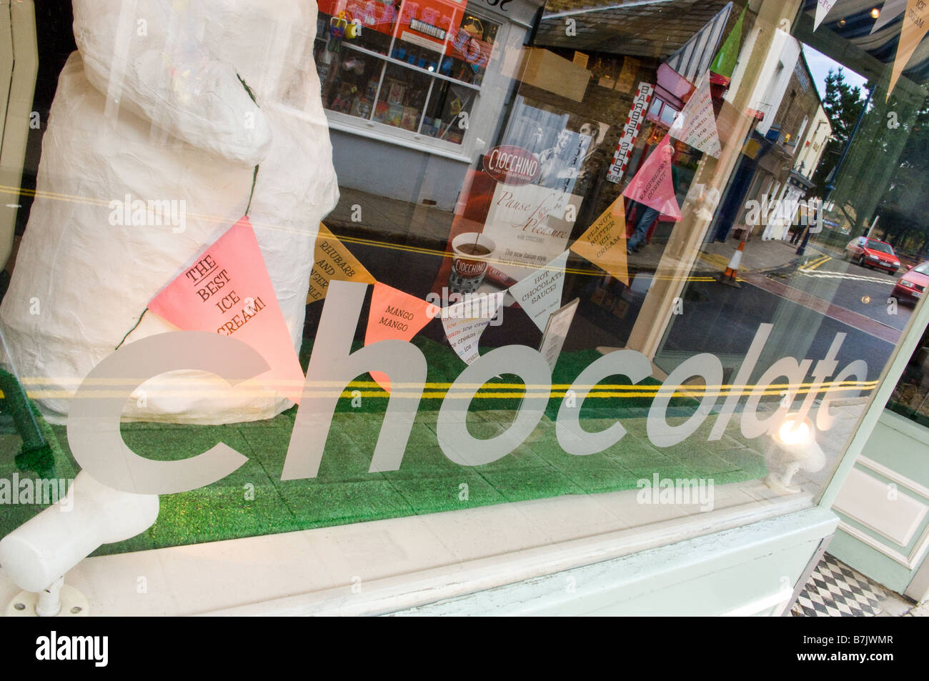 Un grande segno di cioccolato nella vetrina di un negozio di cioccolato con righe di bunting dietro di esso a parlare dei loro gelati in vendita. Foto Stock