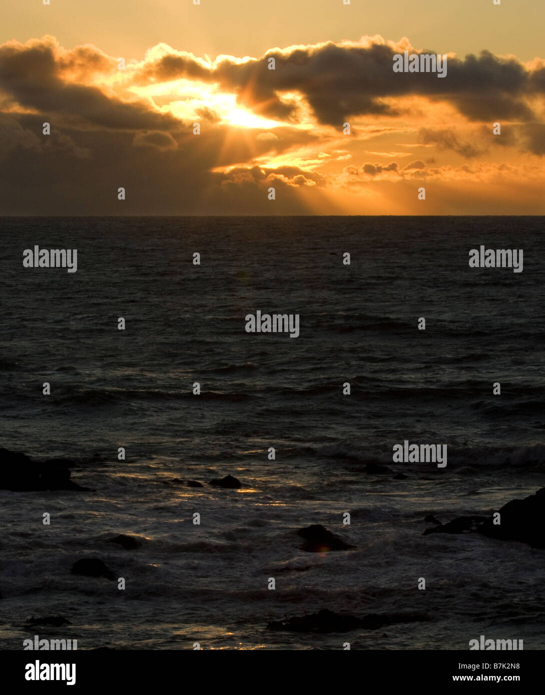 Il sole del tramonto sull'Oceano Pacifico attraversa le nuvole Foto Stock