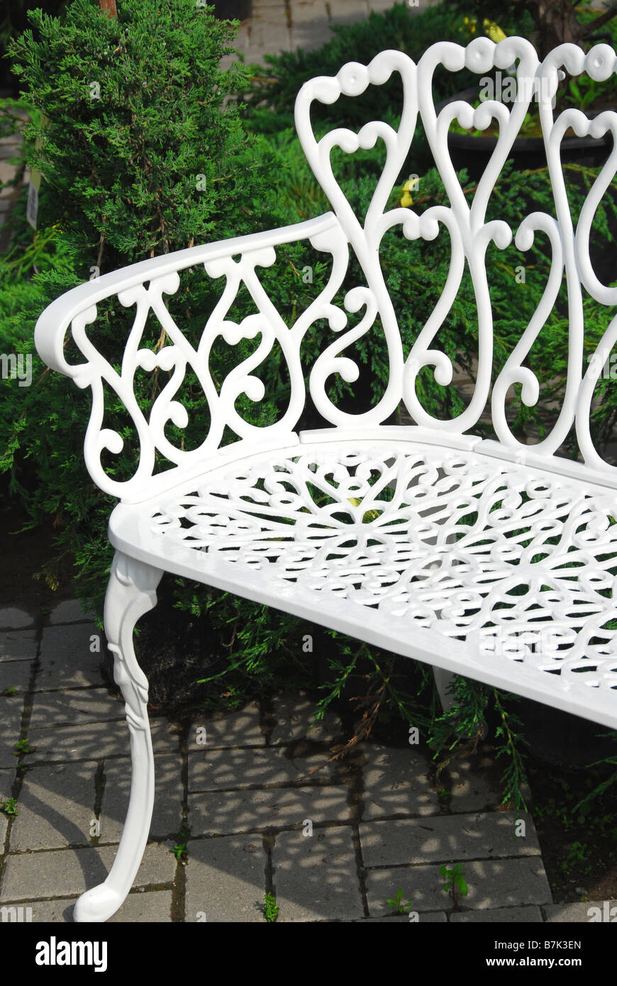 Bianco in ferro battuto panca in un giardino Foto Stock
