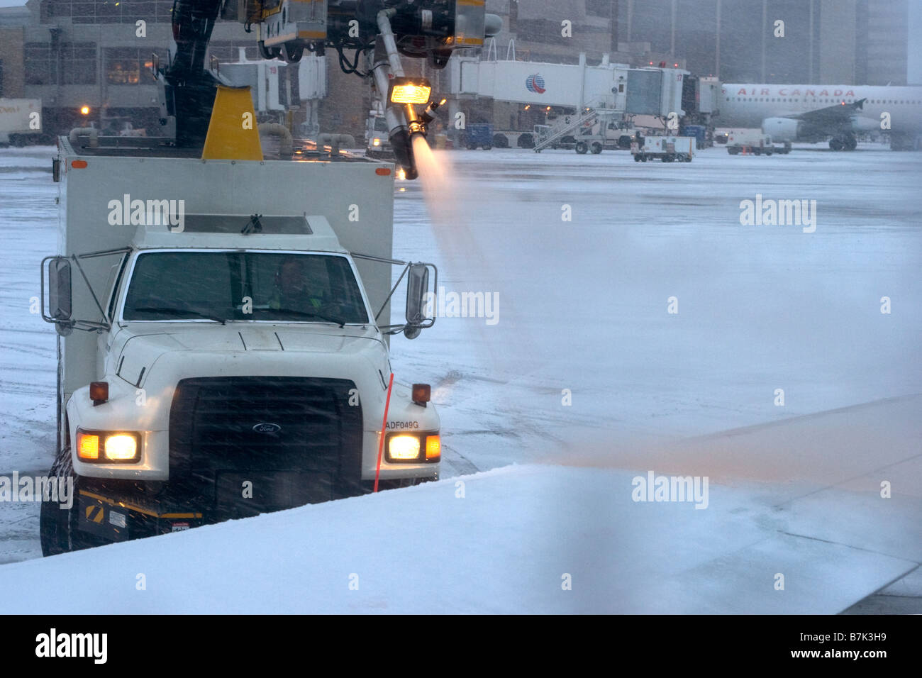 L'equipaggio di terra dell'aeroporto in camion spruzzerà liquido di sbrinamento sull'ala dell'aereo per rimuovere neve e ghiaccio prima del decollo in inverno Foto Stock