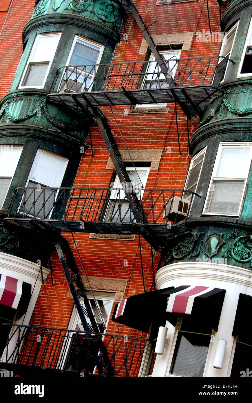 Frammento di una casa in mattoni rossi in Boston storico North End con balconi in ferro battuto e delle uscite di sicurezza Foto Stock