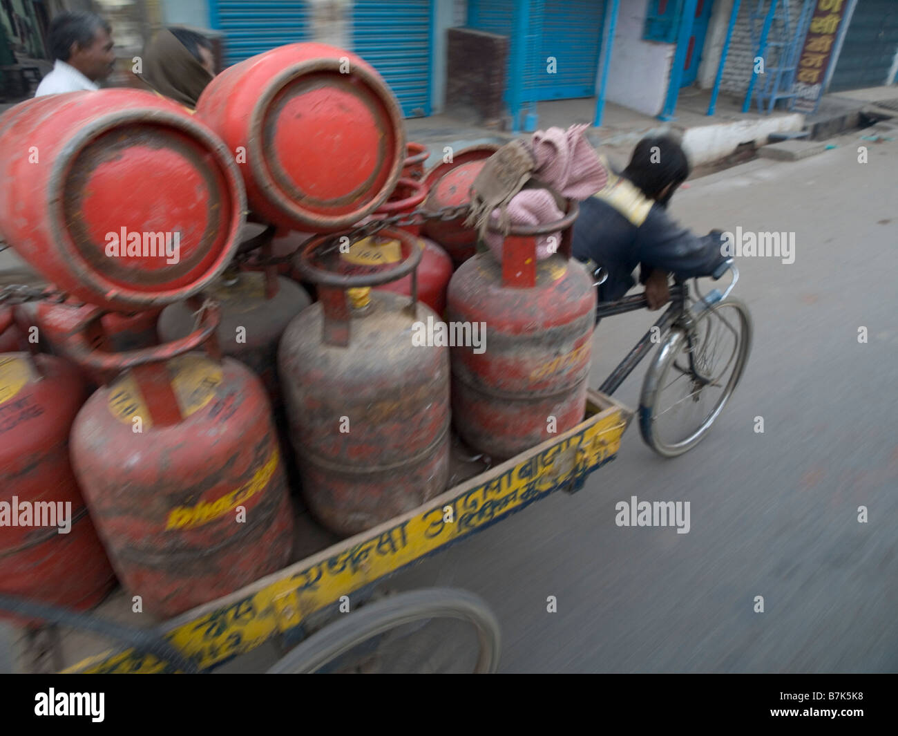 Un lavoratore indiano spinge un risciò bicicletta con bombole di gas in Varanasi Uttar Pradesh Foto Stock