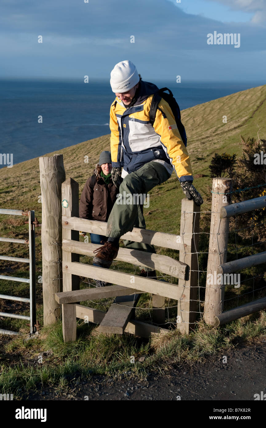 Due persone a piedi lungo il Ceredigion sentiero costiero attraversando un di legno stile West Wales UK Foto Stock