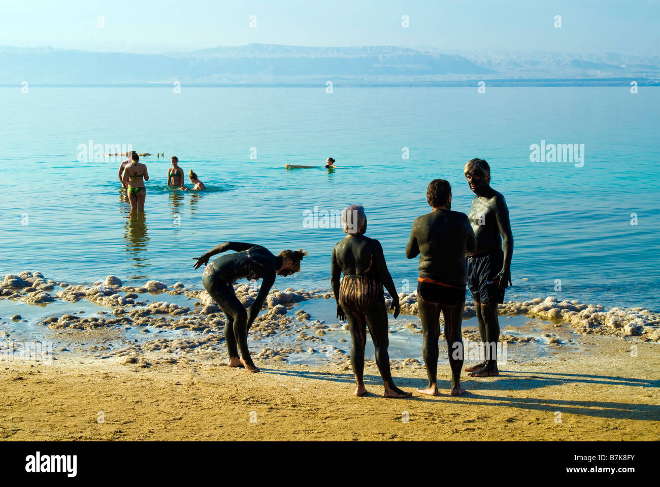 Persone coperte in nero fango del Mar Morto e sali che terapeutico hanno proprietà curative che sono altamente benefico Foto Stock