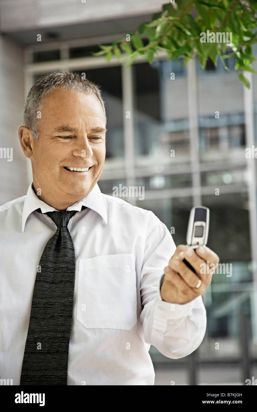 L'uomo con il suo telefono cellulare, sorridente Foto Stock