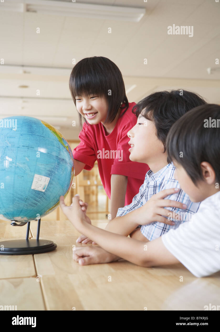 Gli studenti della scuola elementare guardando il globo terrestre Foto Stock