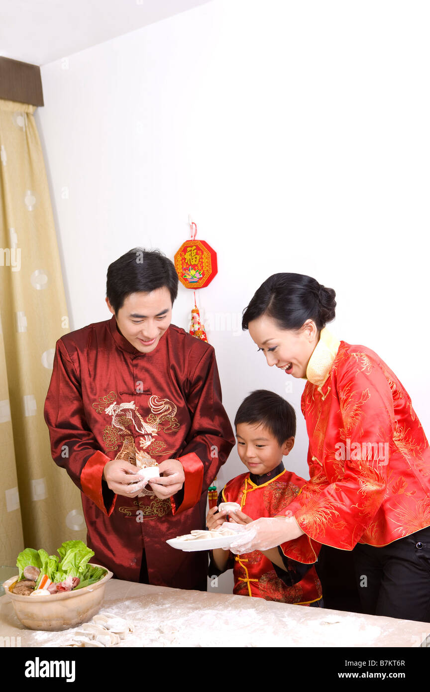 Famiglia in abiti tradizionali rendendo gnocco insieme Foto Stock