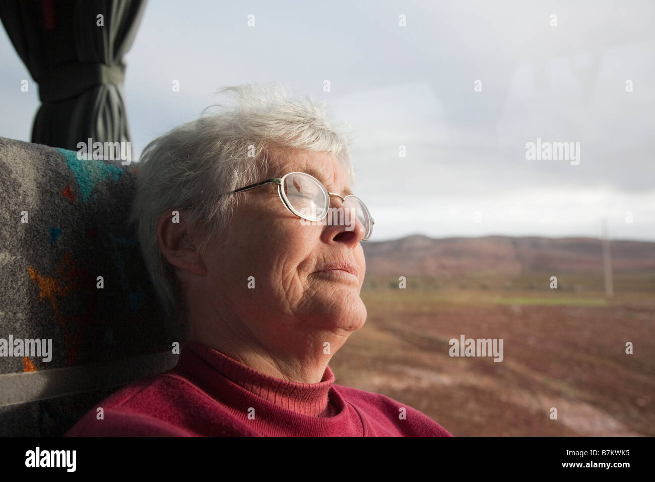 Stanco senior donna addormentata su un pullman sedile da una finestra mentre viaggia su un lungo viaggio. Foto Stock