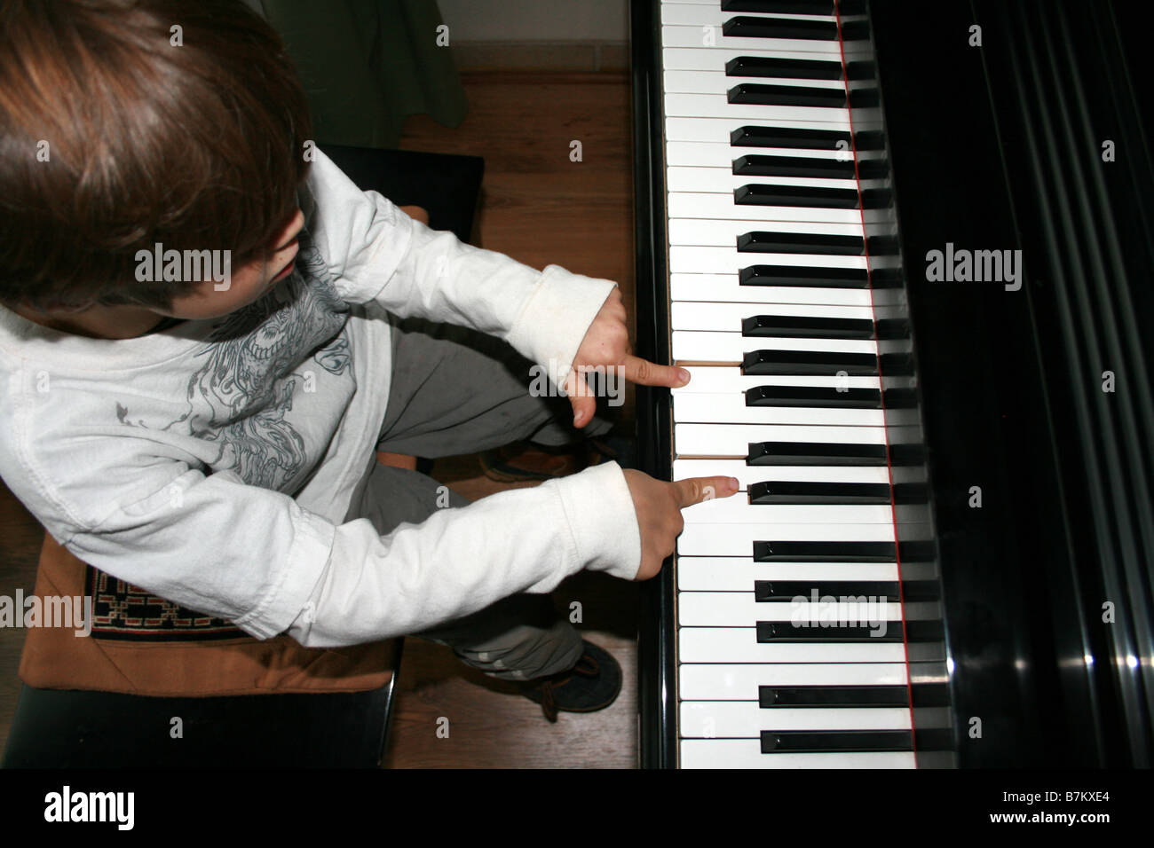 6 anno vecchio ragazzo giocando un pianoforte per la prima volta, la sperimentazione con le dita e suono Foto Stock