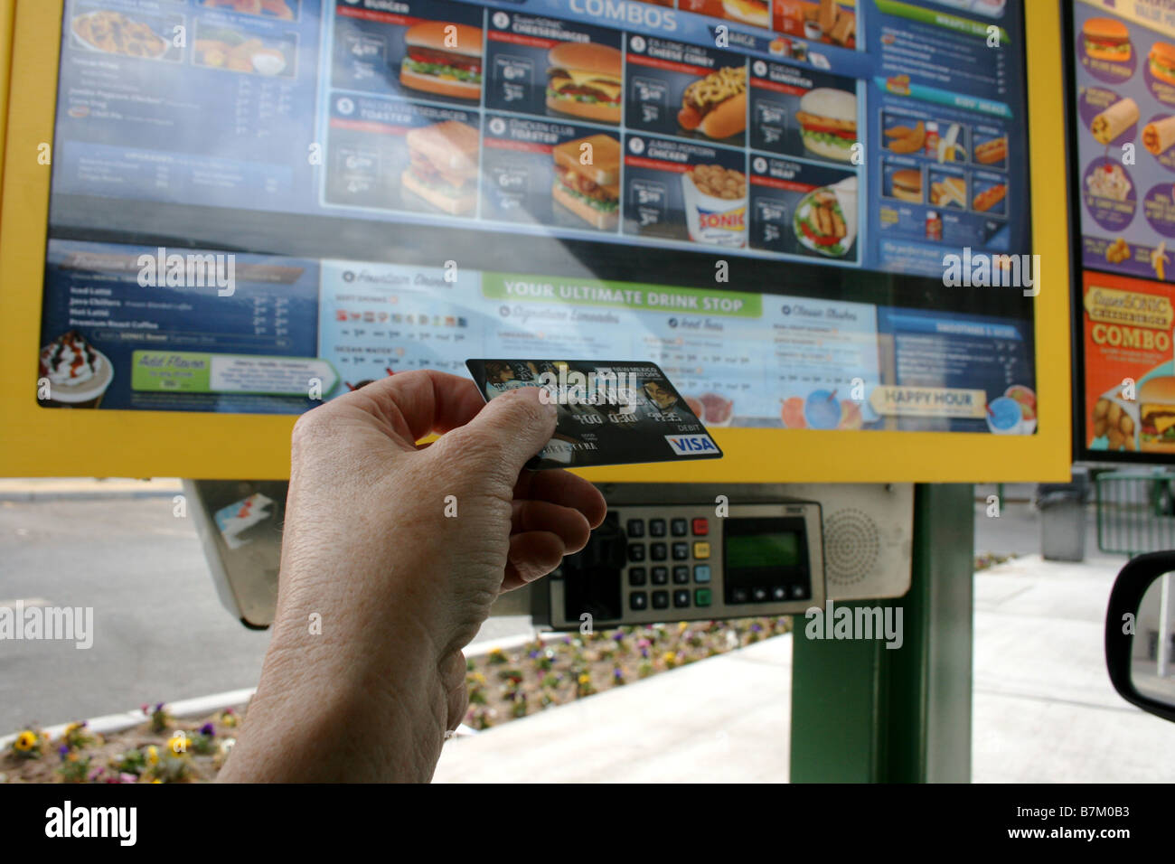 Persona in possesso di carta di credito pronti a strisciare al fast food drive fino ristorante, self-pay Foto Stock