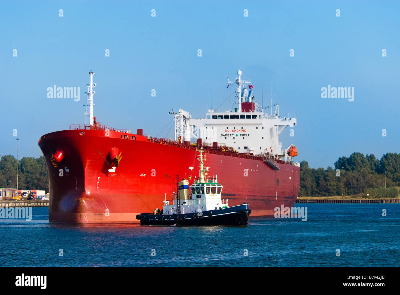 Un enorme red petroliera e un rimorchiatore a traino durante il lavoro Foto Stock